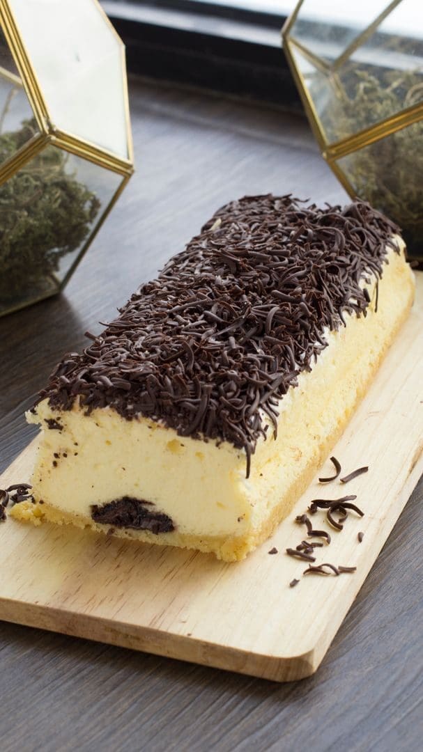 Scrumptious chocolate-topped cheesecake on wooden board with elegant presentation.