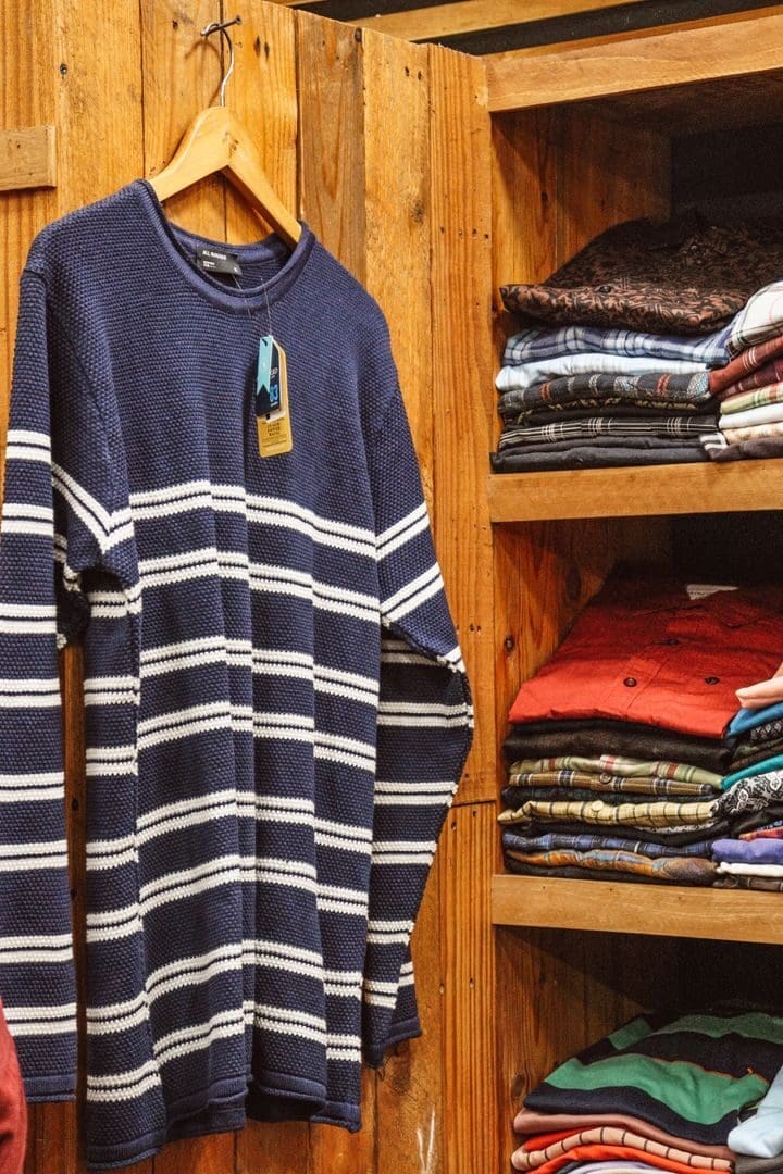 Cozy rustic wardrobe with a blue striped sweater on a hanger and folded clothes.