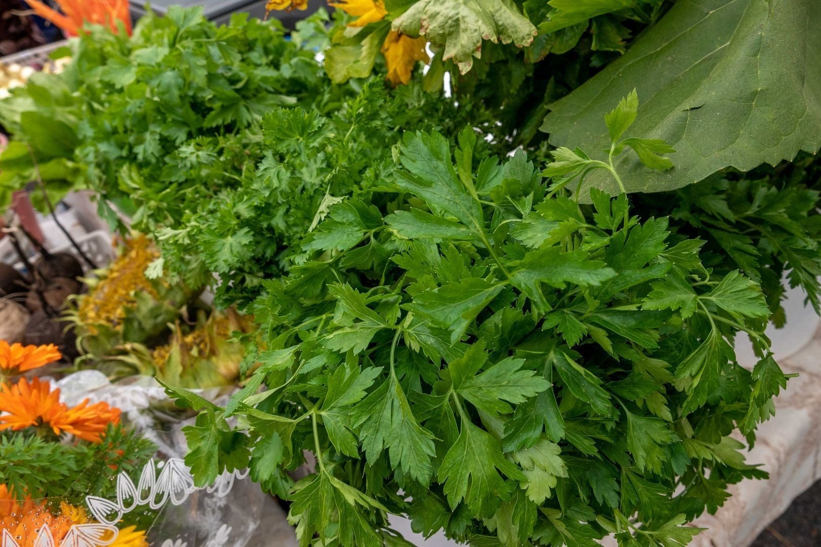 Close-up of fresh parsley and marigolds at a farmer's market display.