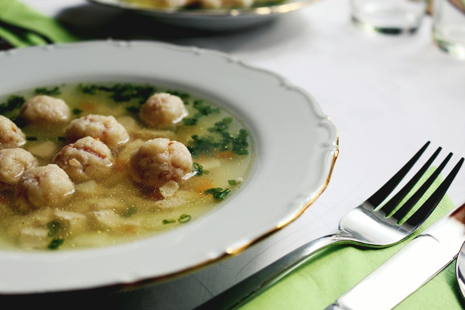 A close-up of a flavorful dumpling soup garnished with herbs, served in an elegant setting.
