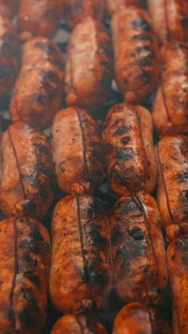 Close-up of grilled sausages cooking on a barbecue grill, perfect for rustic BBQ themes.