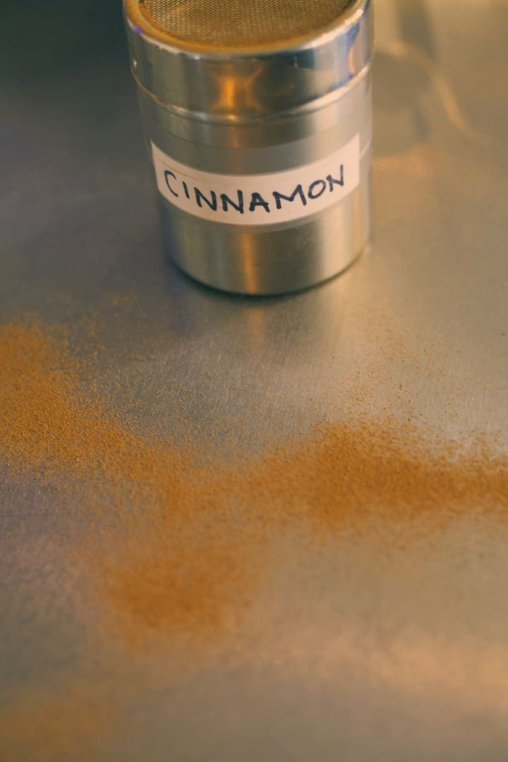 Close-up of cinnamon powder scattered near a labeled metal container.
