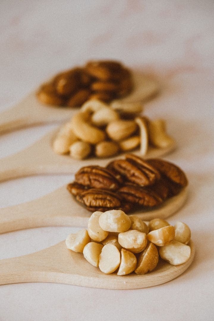 Close-up of assorted nuts on wooden spoons, highlighting variety and nutrition.
