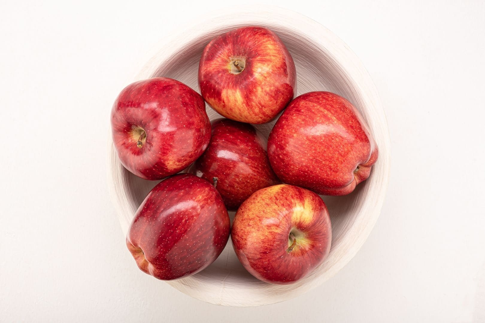 High angle view of fresh red apples in a wooden bowl, highlighting healthy snacking options.