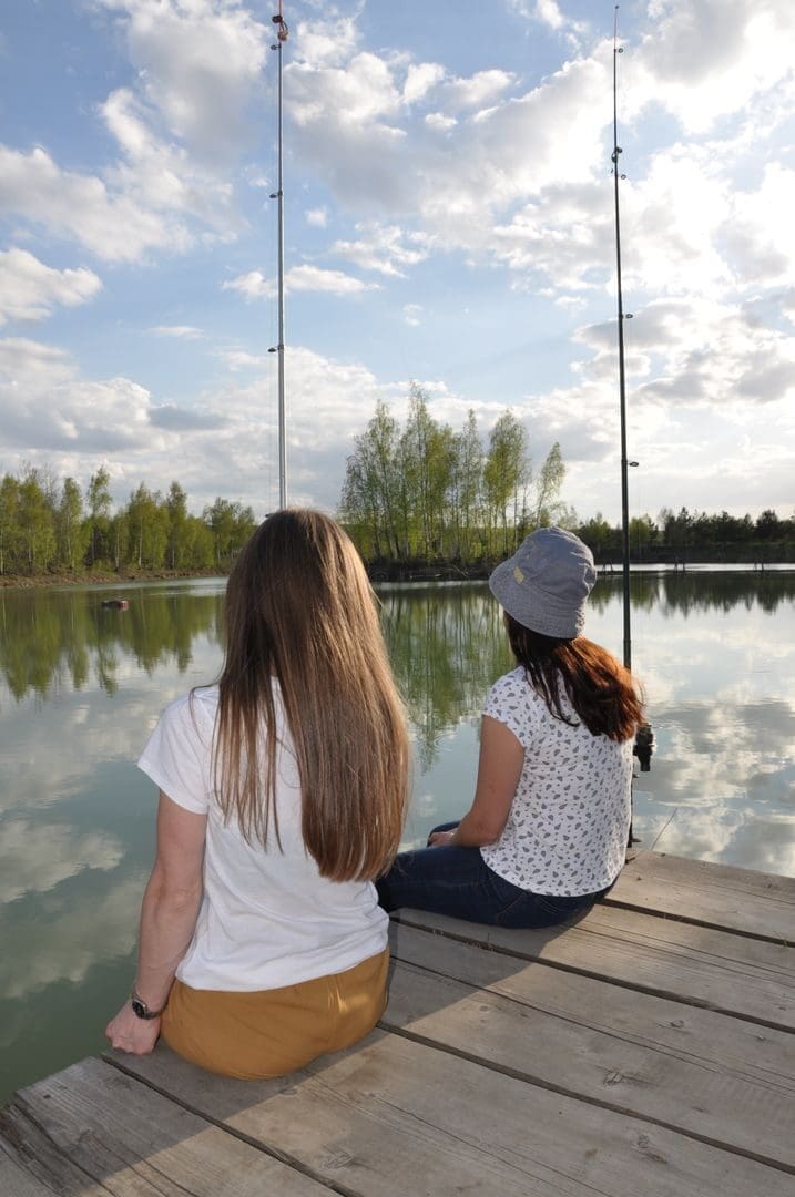 Two friends relaxing on a dock by the lake, enjoying a peaceful fishing day.