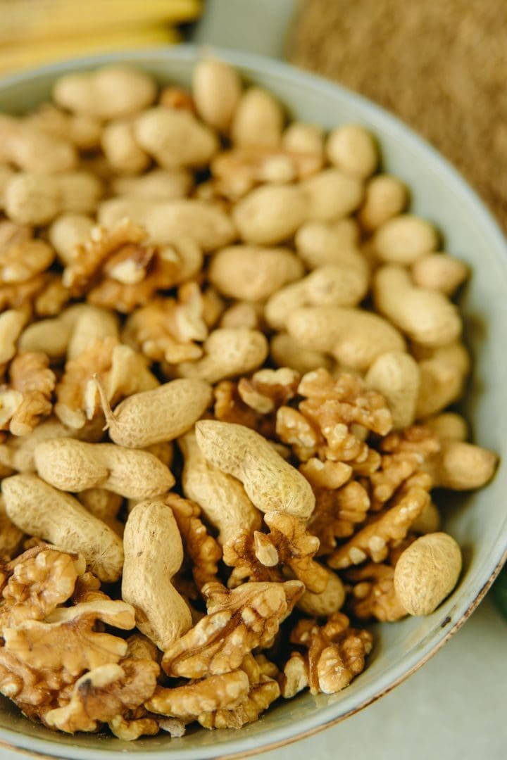 High angle view of shelled walnuts and unshelled peanuts in a bowl, perfect for food photography.